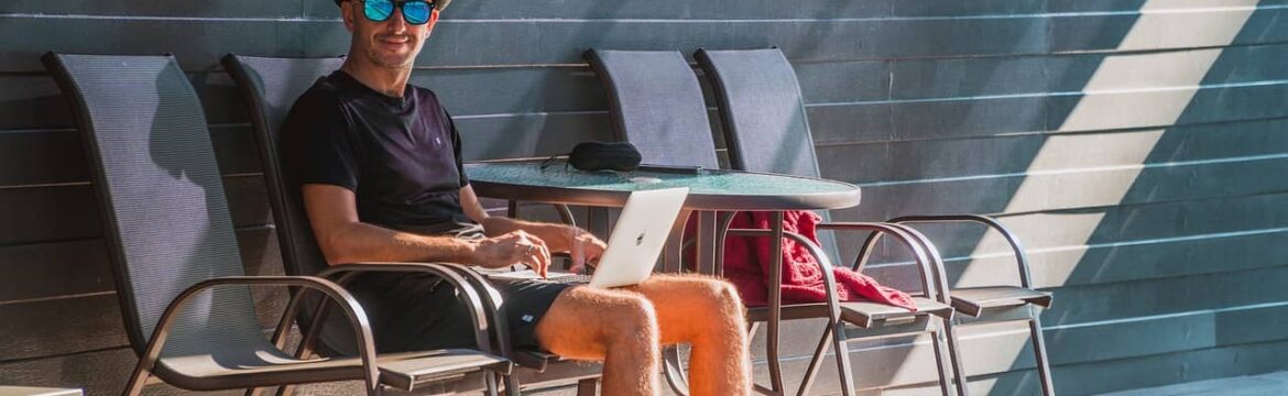 Man sitting on a patio chair with laptop shows the ergonomic cost of being a digital nomad